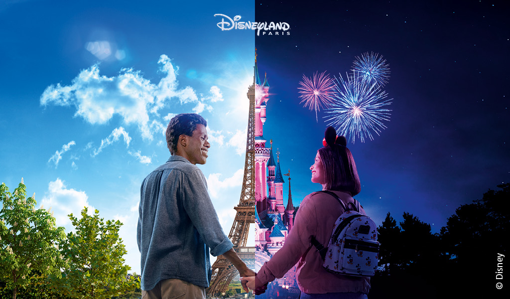 Ein lächelndes Paar hält Händchen vor farbenfrohem Disneyland Paris mit Feuerwerk